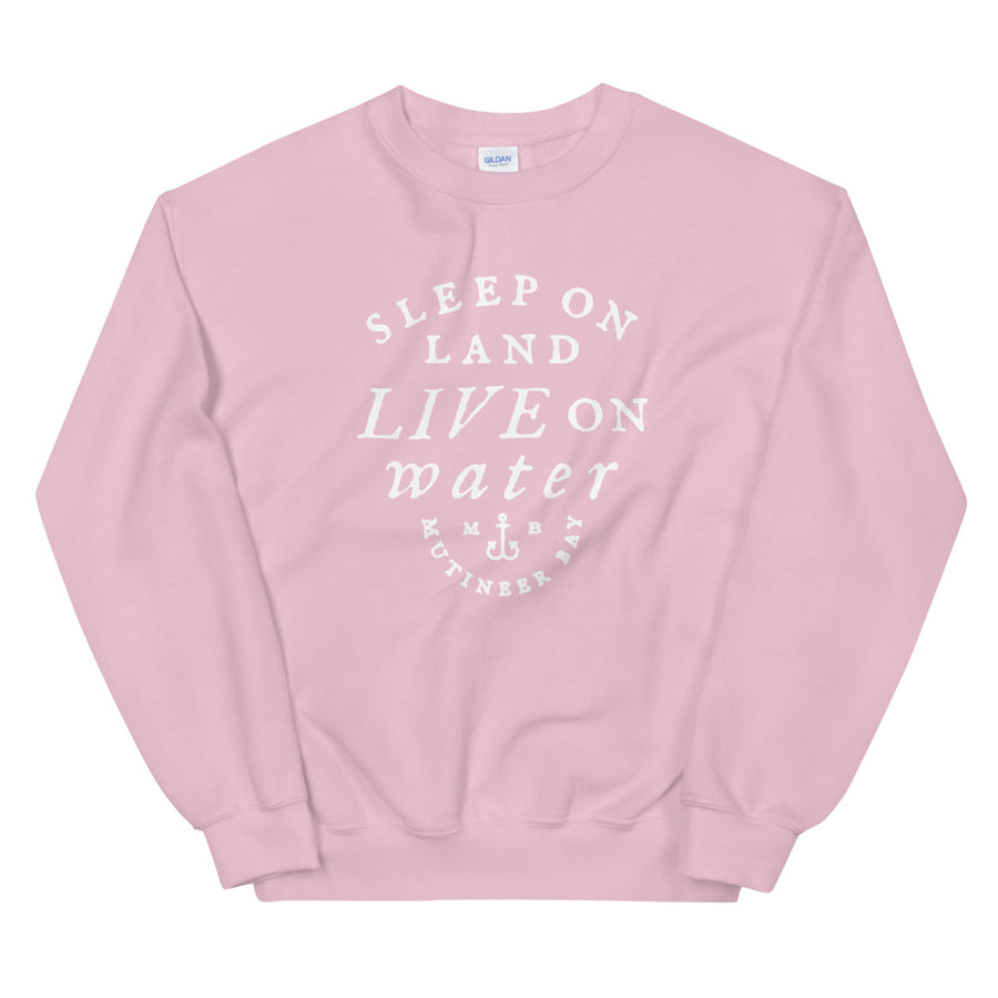 Pink unisex sweatshirt with wording in white, "Sleep on Land, Live on Water" written in black artistic lettering on front. Underneath this is very small semi circle stating "Mutineer Bay" centered with small anchor. All lettering and images are in white.