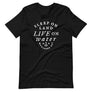 Black unisex t-shirt with wording in white, "Sleep on Land, Live on Water" written in black artistic lettering on front. Underneath this is very small semi circle stating "Mutineer Bay" centered with small anchor. All lettering and images are in white.
